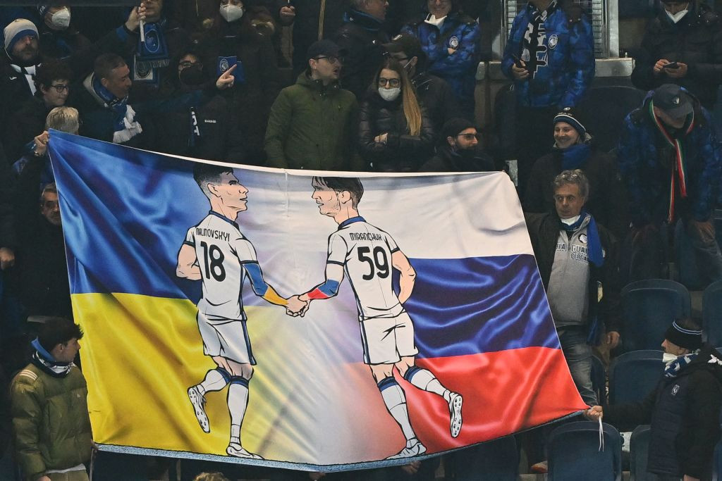 Банер фанів Аталанти, на якому Малиновський і Міранчук тиснуть одне одному руки на фоні українського та російського прапорів